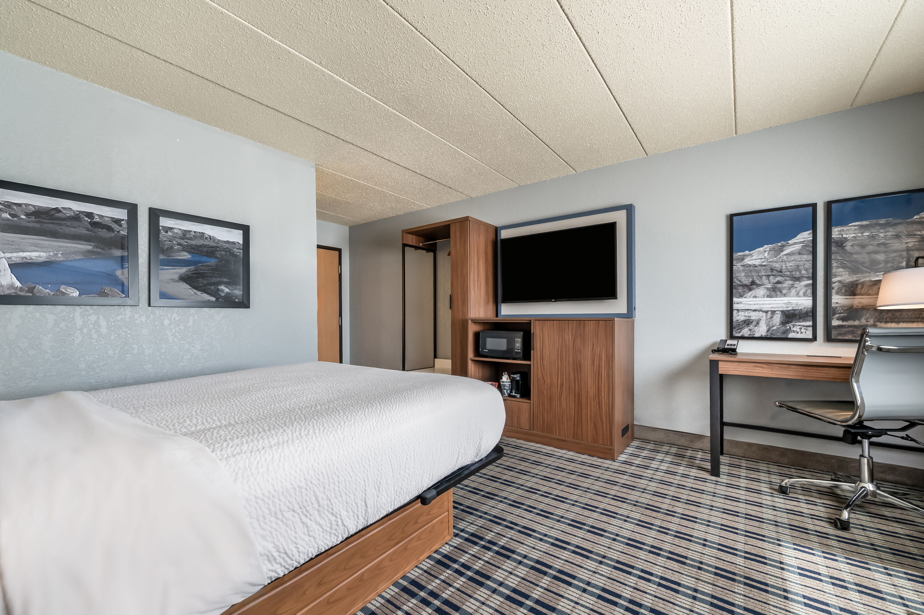Queen bed guest room at the AmericInn by Wyndham Dickinson in Dickinson, North Dakota