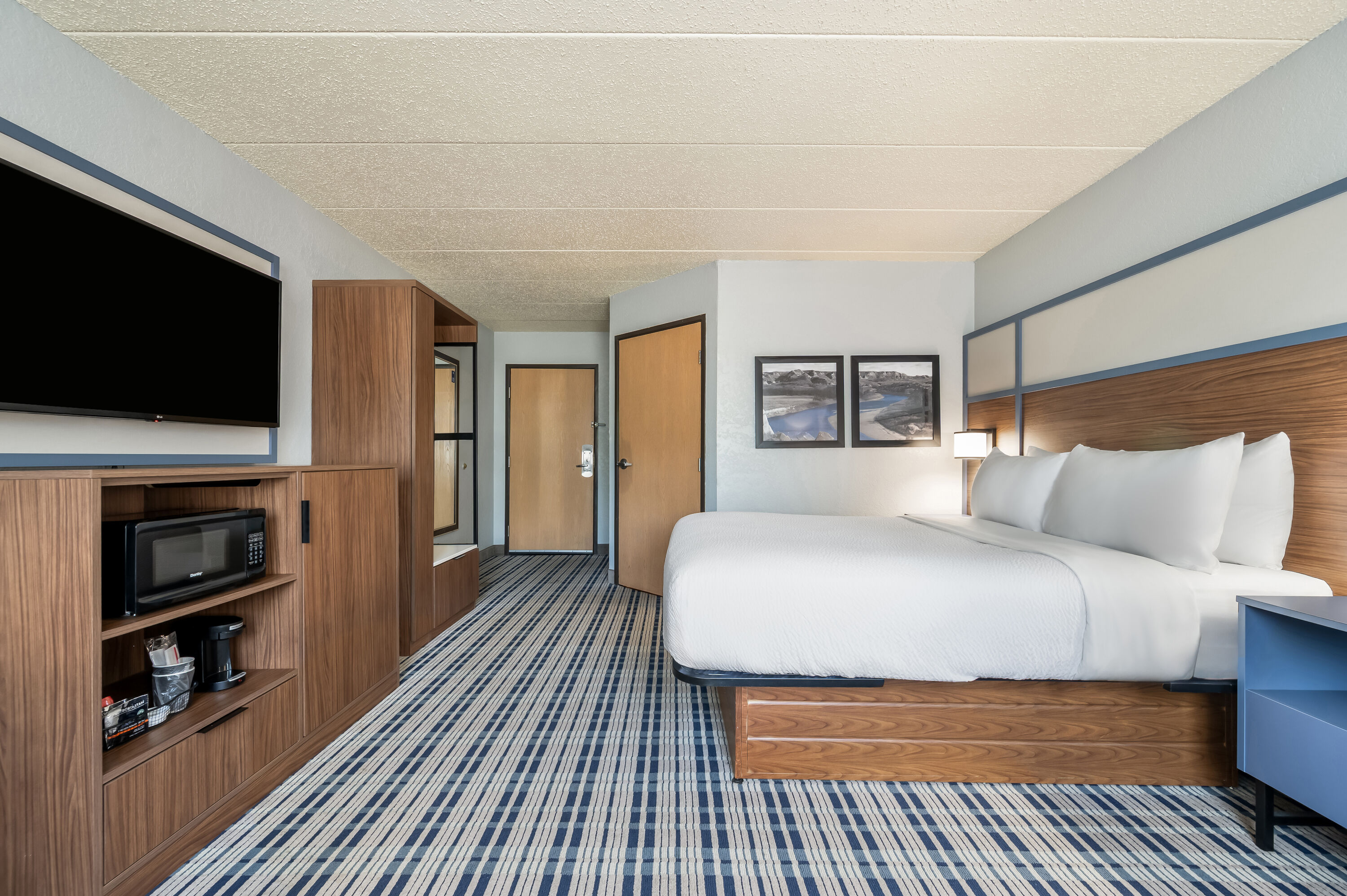 Queen bed guest room at the AmericInn by Wyndham Dickinson in Dickinson, North Dakota