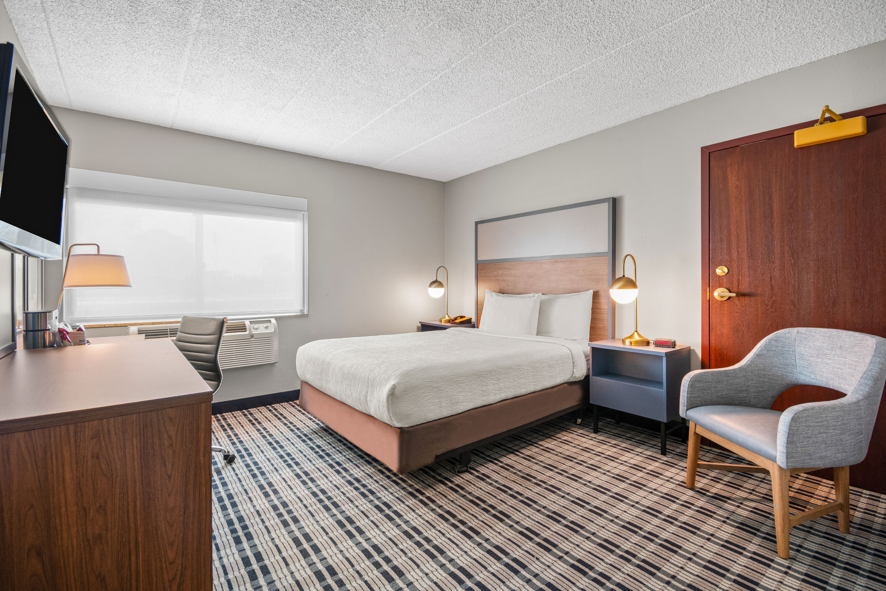 Queen bed guest room at the AmericInn by Wyndham Beloit in Beloit, Wisconsin