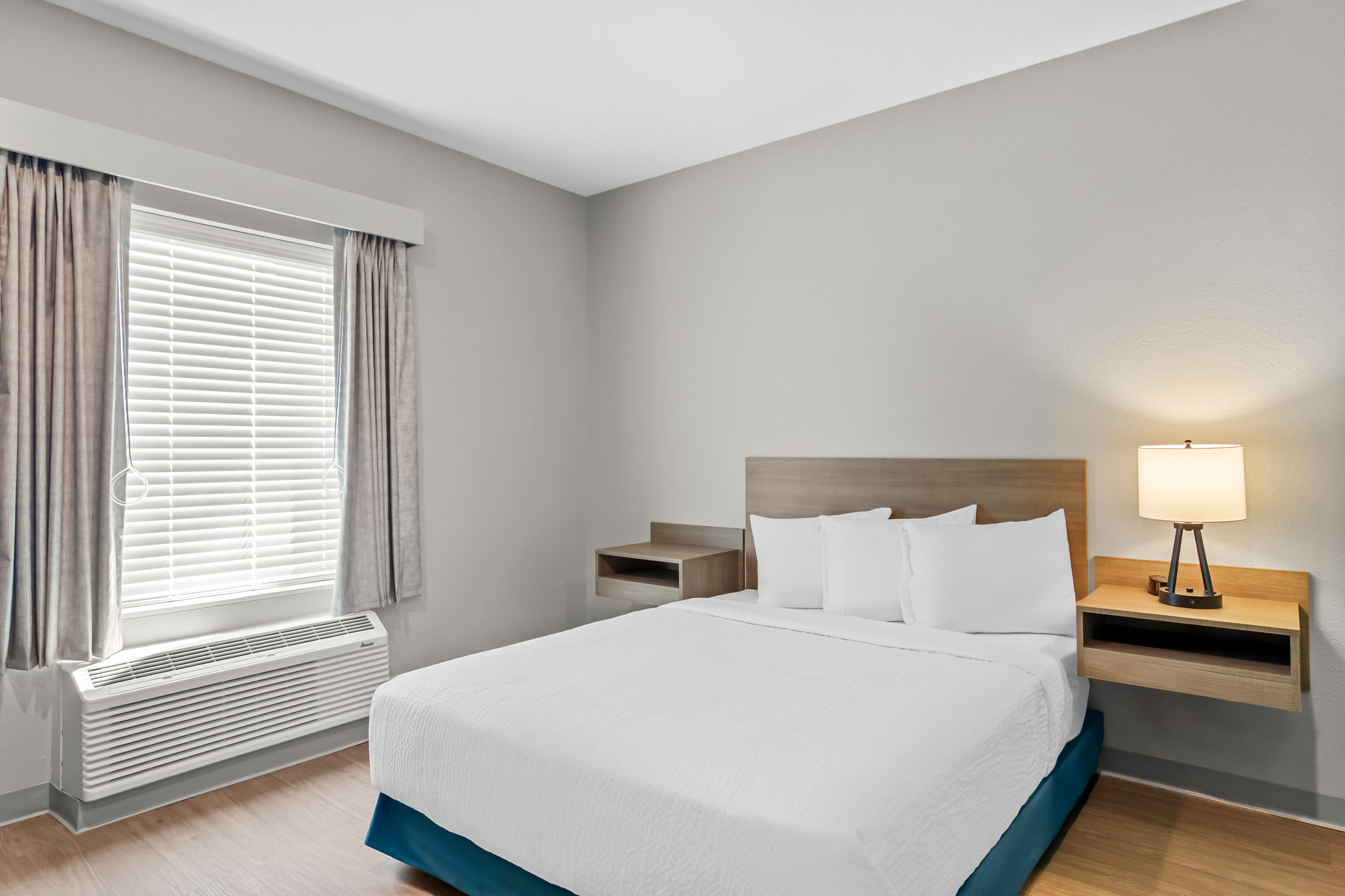 Queen bed guest room at the ECHO Suites Extended Stay by Wyndham Middleburg in Middleburg, Florida