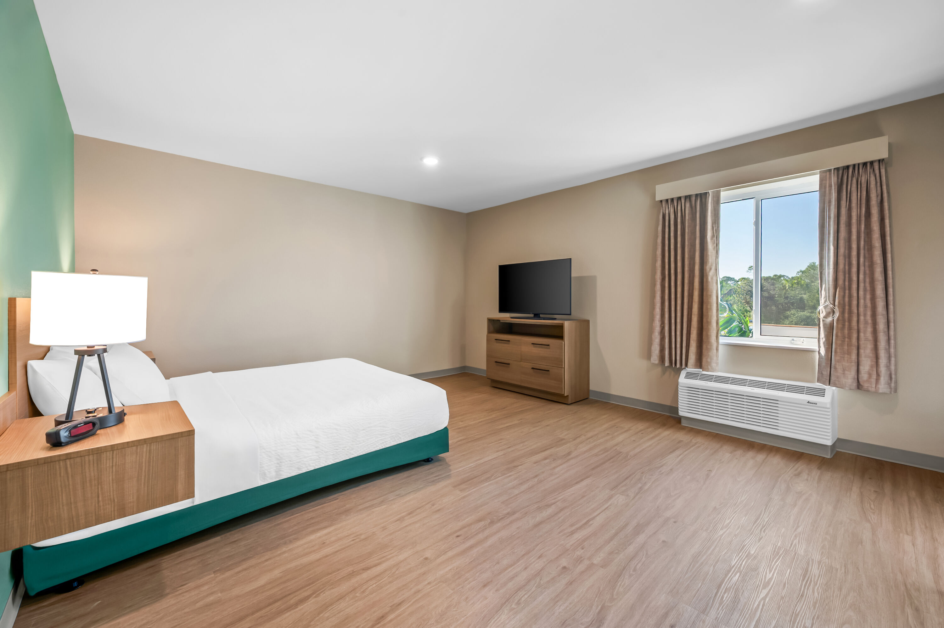 Queen bed guest room at the ECHO Suites Extended Stay by Wyndham Naples in Naples, Florida