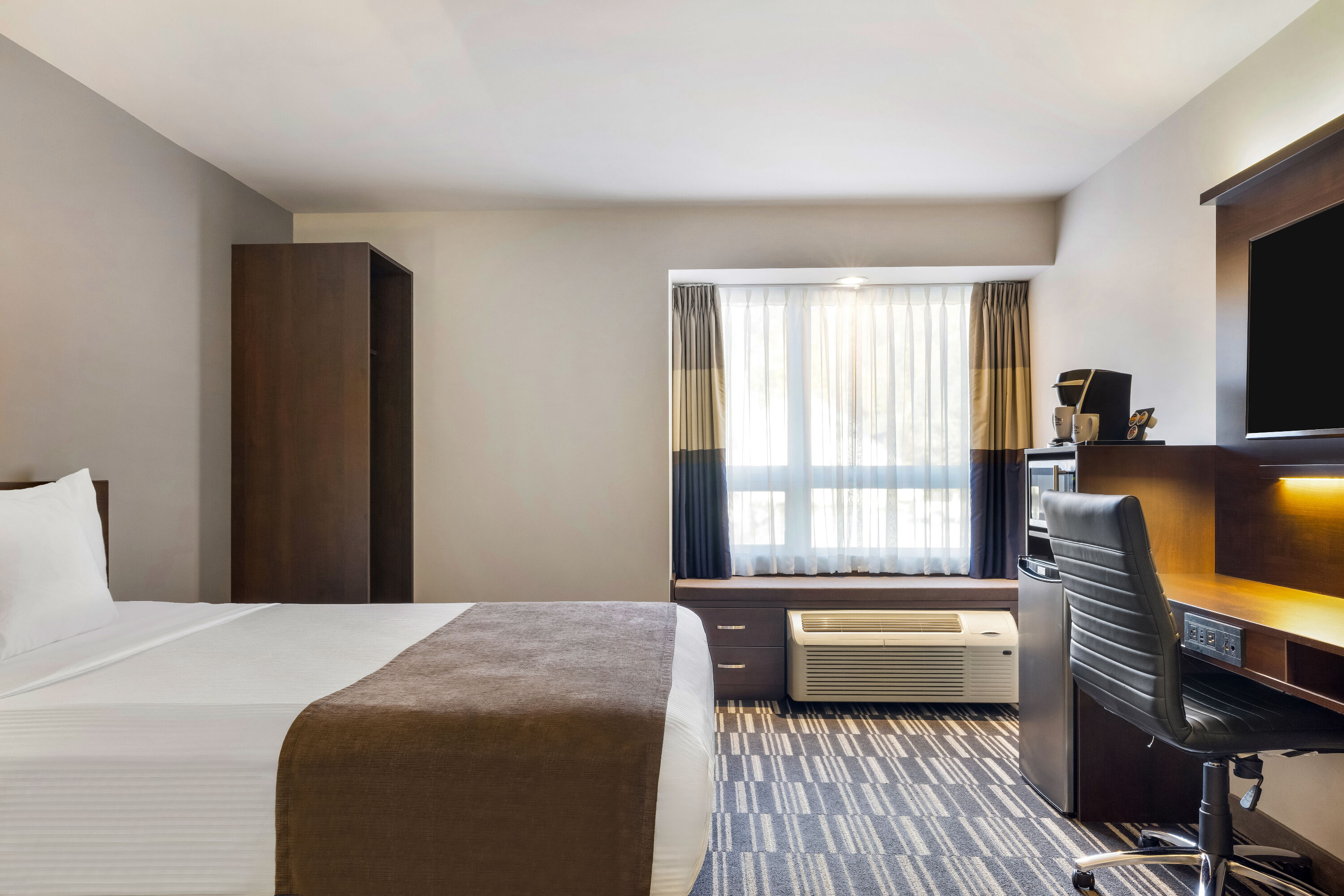 Queen bed guest room at the Microtel Inn & Suites by Wyndham Mont Tremblant in Mont-Tremblant, Quebec