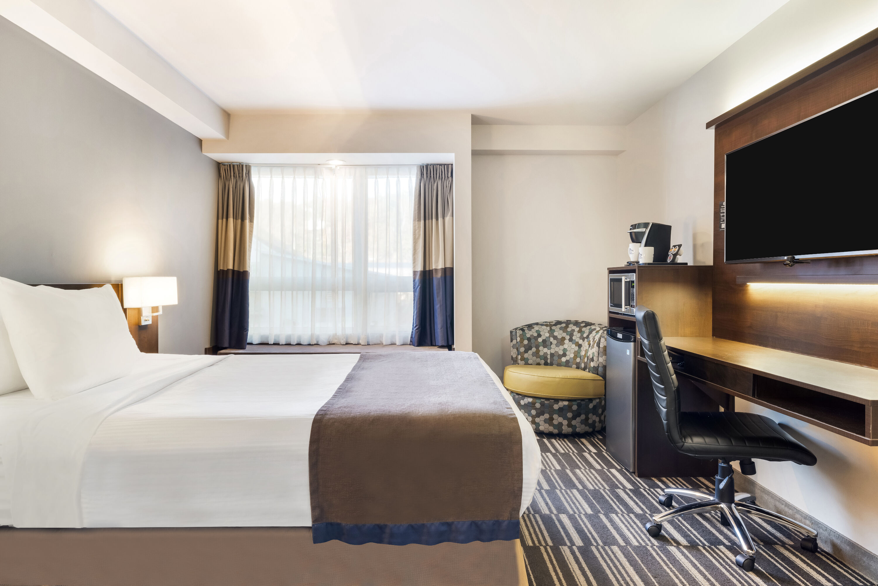 Queen bed guest room at the Microtel Inn & Suites by Wyndham Mont Tremblant in Mont-Tremblant, Quebec